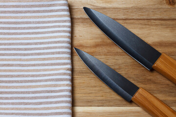 Kitchen accessories. Salt and pepper shaker, kitchen towel. Black ceramic knife, white plate. Fork and cutting board.