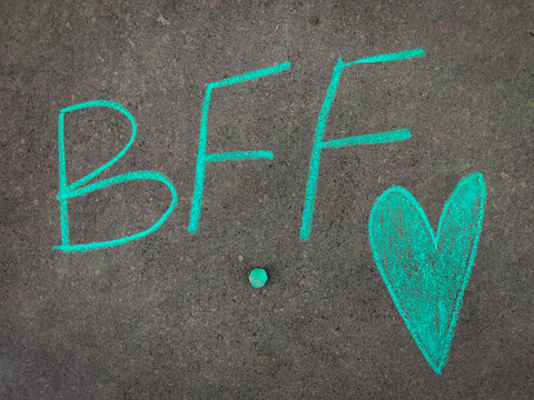 The inscription text on the grey board, BFF (Best friend forever) with hand drawn green color love symbol. Using color chalk pieces.