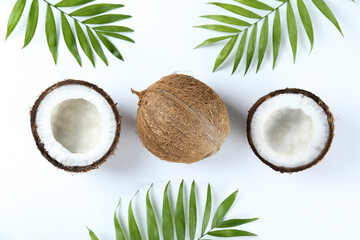Fototapeta na wymiar Top view shot of coconuts, whole and cracked on halves on paper textured background with a lot of copy space for text. Bacground with raw fruit of tropical palm. Flat lay.