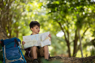 American Little boy child reading map in the forest  trail adventure at summer holiday