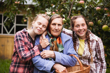 Portrait of granddaughters with their grandmother in   apple orchard