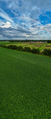 Aerial panorama view shot with drone of a rainbow over stormy sky. Rural landscape with rainbow over dark stormy sky in a countryside at summer day. High quality photo