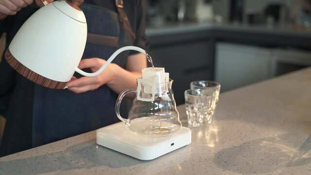 Female worker making fresh tea and standing at table in cafe kitchen indoors spbas.