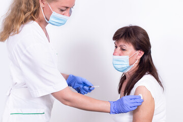 Female doctor or nurse giving shot or vaccine to patient's shoulder. Vaccination and prevention against flu, virus pandemic, coronavirus. Mandatory vaccination of elderly people from the risk group.