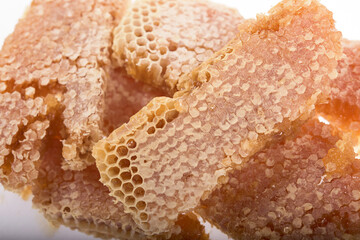Pieces of honeycomb, filled with liquid honey, on a white background