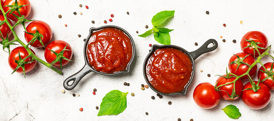 Homemade tomato sauce with spices and herbs on white marble table top view.