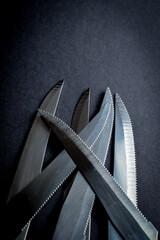 kitchen knife blades on dark gray background, blue toned image, abstract background 