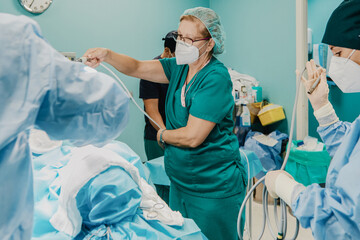 Medical doctors preparing patient in operating room at modern hospital - Focus on middle nurse