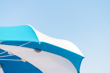 Fototapeta na wymiar Blue and white beach umbrella on the background of the blue sky.Creative background.Summer concept.Copy space for text.