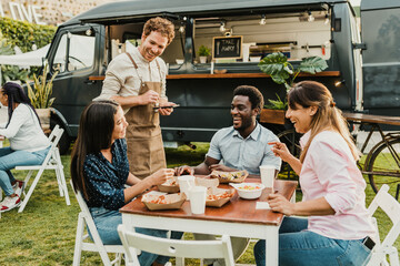 Friendly waiter taking order from diverse friends near food truck - Powered by Adobe