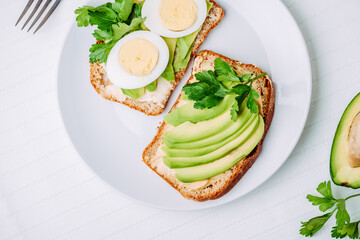 Toast with avocado and egg on white plate. Top view. Healthy breakfast