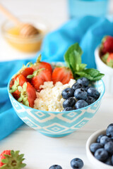 Bowl of cottage cheese with blueberry, strawberry and honey. Soft focus