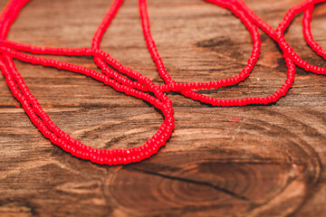 Red beads on a wooden background. Beads and handicrafts for creativity.