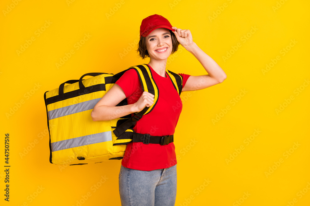 Wall mural photo portrait of woman in red uniform smiling keeping rucksack delivery service isolated vivid yell