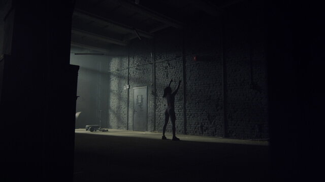 Athletic Sportswoman Throwing Fit Ball Against Concrete Wall In Loft Building