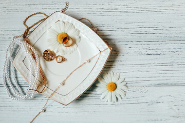 Delicate daisies close-up with gold jewelry. Chains, pendants, rings on a stand.