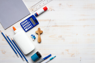 school supplies on white wood background with small wooden cross with copy space