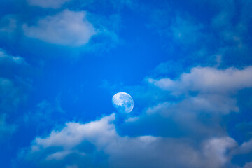 Lua entre as nuvens e céu azul da manha