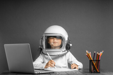 the child studies remotely at school, wearing an astronaut's helmet. back to school