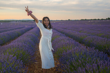 outdoors romantic portrait of young happy and attractive woman in white summer dress enjoying carefree at beautiful lavender flowers field in travel and holiday concept