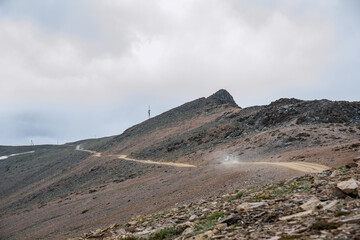 The car rides a dusty sandy road in a mountainous area. Traveling in Russia in the summer.