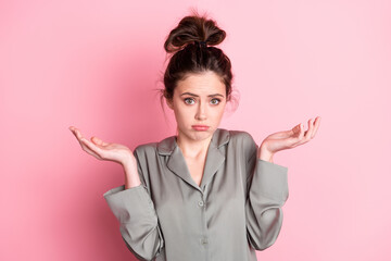 Photo portrait of girl in pajama having doubt unsure shrugging shoulders isolated on pastel pink...