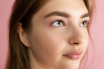 Fototapeta premium Close-up beautiful adorable young girl posing isolated over pink studio background. Natural beauty, spa, cosmetics and aesthetic cosmetology concept.