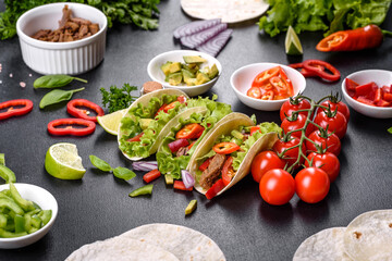 Mexican tacos with beef, tomatoes, avocado, onion and salsa sauce
