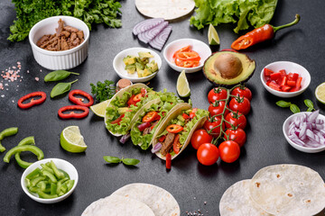 Mexican tacos with beef, tomatoes, avocado, onion and salsa sauce