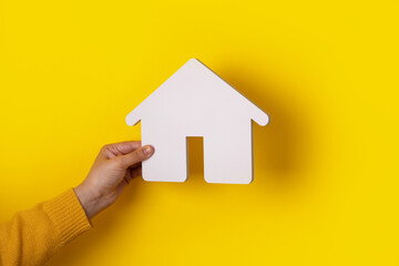 house in hand over yellow background, concept of buying a home on credit