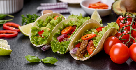 Mexican tacos with beef, tomatoes, avocado, onion and salsa sauce