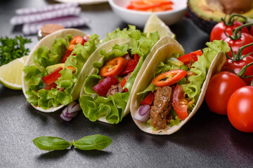 Mexican tacos with beef, tomatoes, avocado, onion and salsa sauce