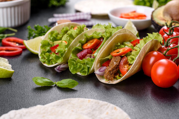 Mexican tacos with beef, tomatoes, avocado, onion and salsa sauce