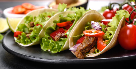 Mexican tacos with beef, tomatoes, avocado, onion and salsa sauce
