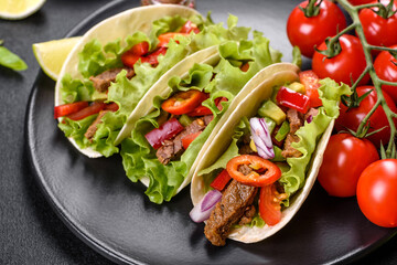 Mexican tacos with beef, tomatoes, avocado, onion and salsa sauce