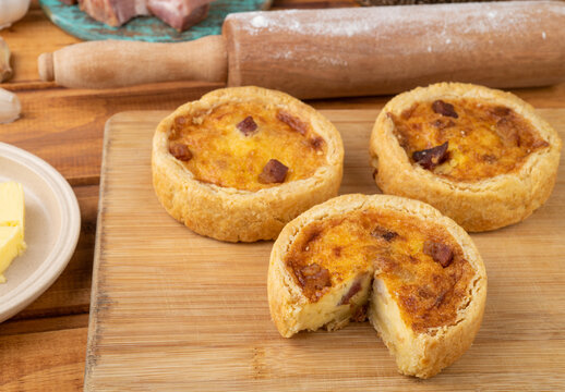Homemade quiche lorraine over wooden board with ingredients