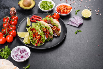 Mexican tacos with beef, tomatoes, avocado, onion and salsa sauce