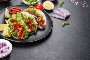 Mexican tacos with beef, tomatoes, avocado, onion and salsa sauce