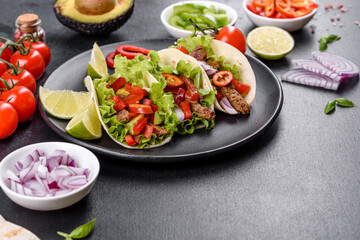 Mexican tacos with beef, tomatoes, avocado, onion and salsa sauce