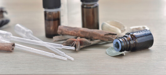 bottles of essential oil and stick of cinnamon and anise on a wooden table