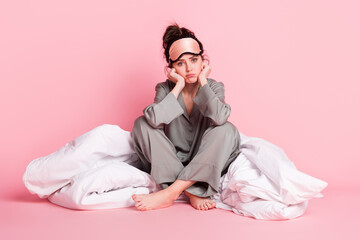 Portrait of attractive sad girl sitting on floor cosy warm soft blanket isolated over pink pastel...