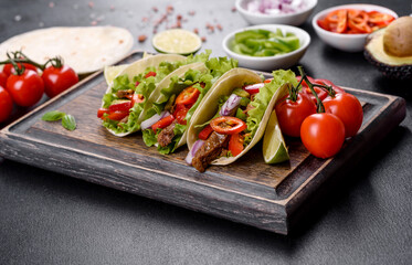 Mexican tacos with beef, tomatoes, avocado, onion and salsa sauce