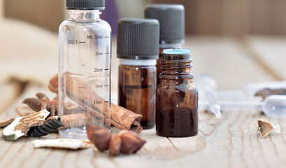 bottles of essential oil and empty graduated bottle with spices  on a wooden table
