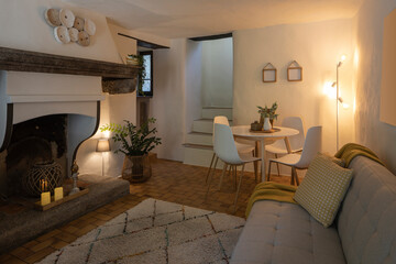 Modern living room of a mountain house with a table, four designer chairs and a comfortable sofa with a blanket