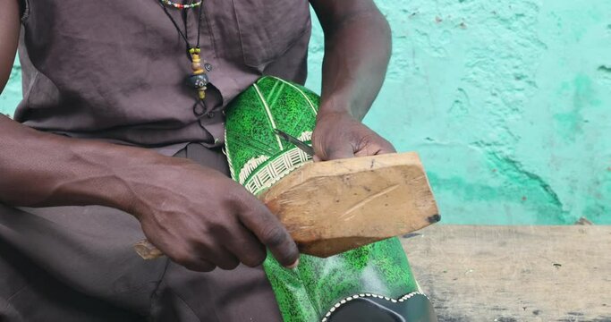 Wood carver working on colorful statue Ghana Africa. Hand tool make work difficult and unique craftsmanship. Tourism, business and home decorations. Handmade product. Products sell in street.
