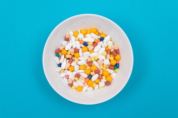 Global Pharmaceutical Industry and Medicinal Products - Colored Pills and Capsules in White Dish on Blue Background