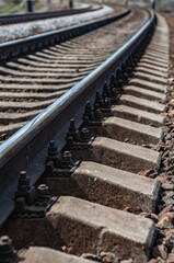 Fastening screws, coarse rubble under railroad. Railway metal rails on concrete sleepers close-up.