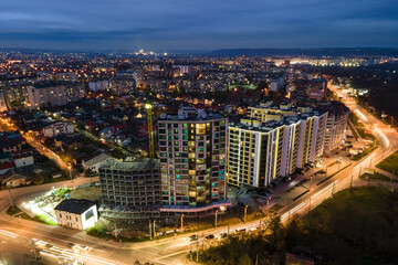 High rise apartment buildings with illuminated windows in city residential area at night.