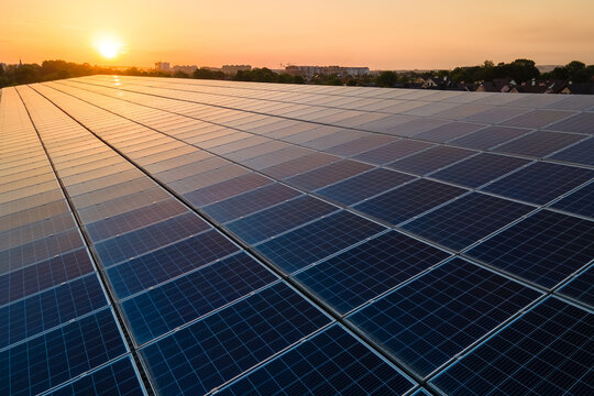 Blue photovoltaic solar panels mounted on building roof for producing clean ecological electricity at sunset. Production of renewable energy concept.