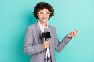 Photo of charming cute schoolboy dressed grey suit glasses smiling holding microphone isolated teal...